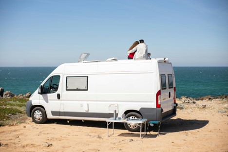 People sitting on top of a van on beach0